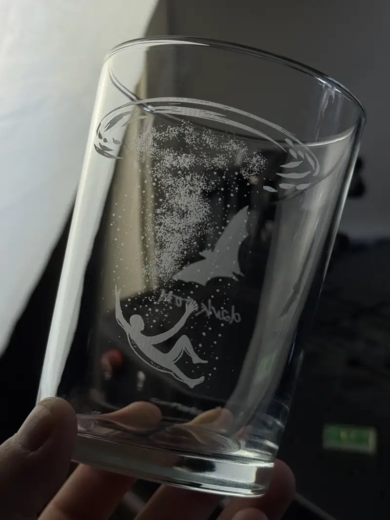 A pint engraved with an illustrated design wrapping around the glass