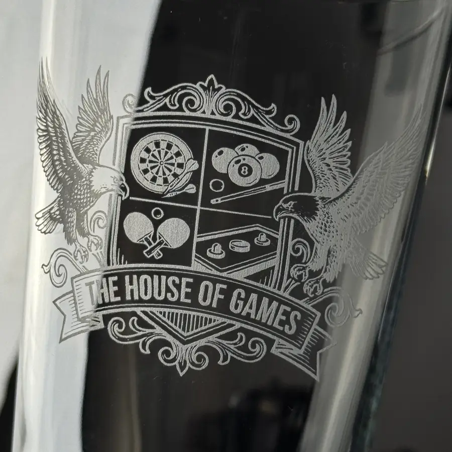 A pint engraved with a detailed illustrated design, showing the depth and texture of the frosted finish