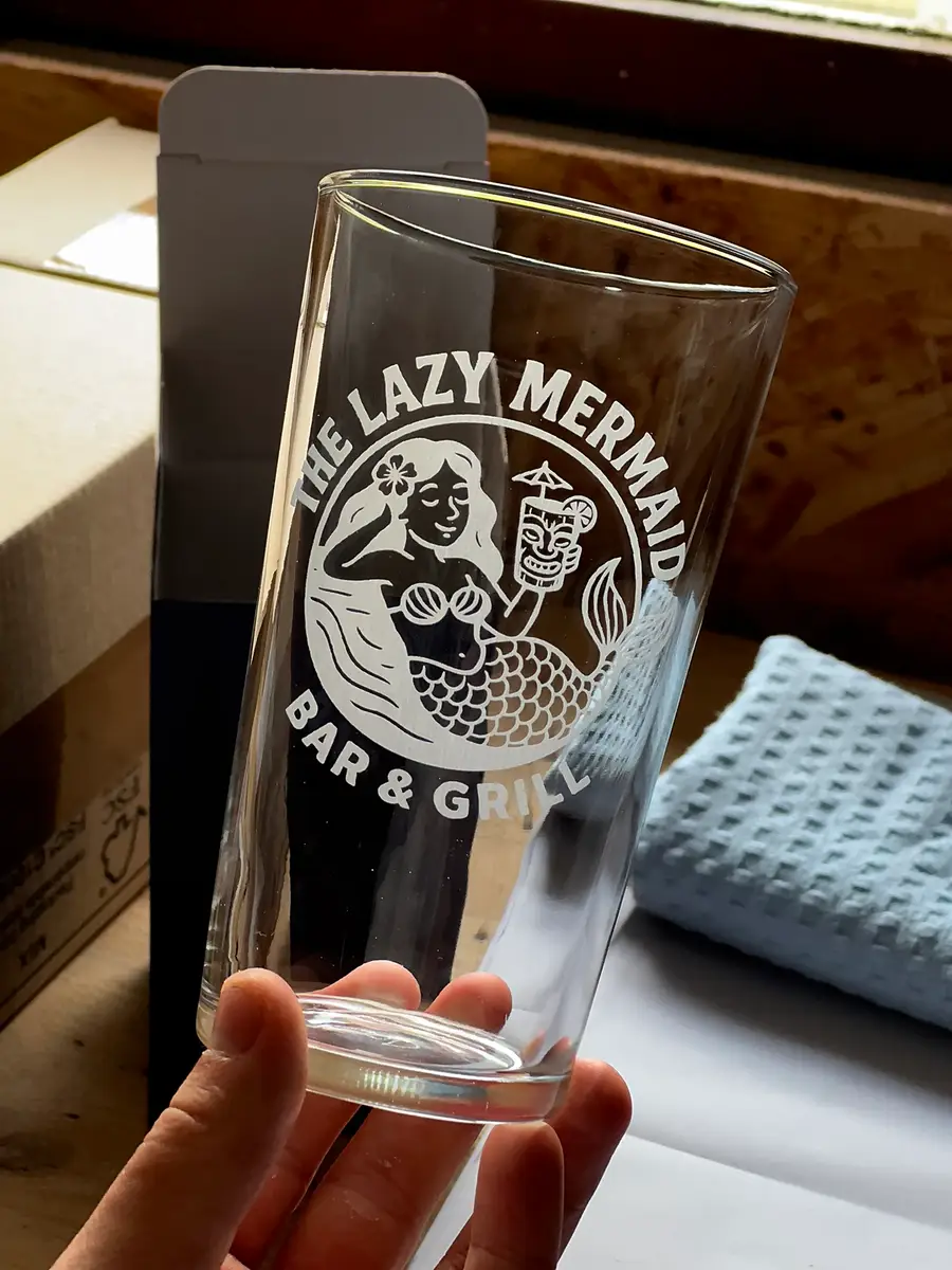 A conical pint engraved with a bar and grill’s logo