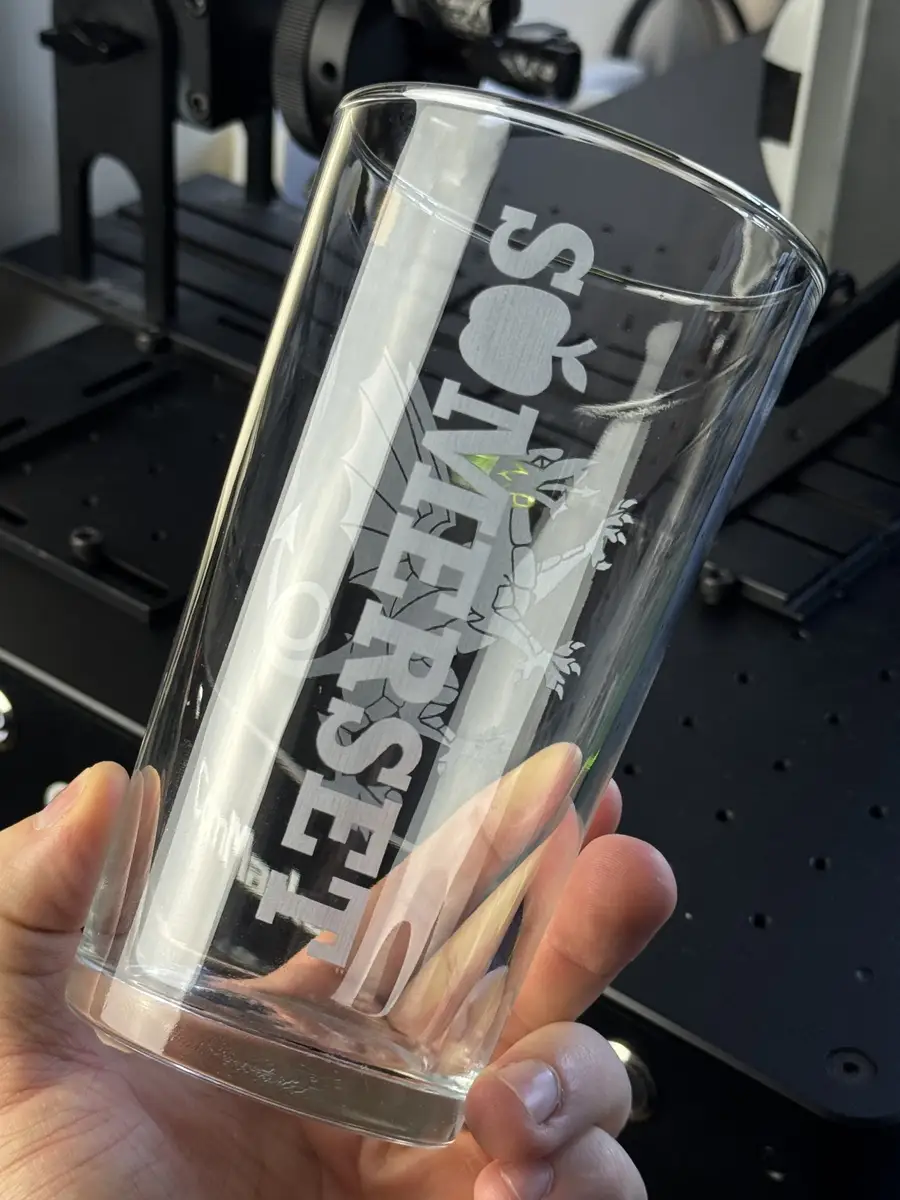 A conical pint engraved with a cider brand crest, showing how the artwork sits on the glass